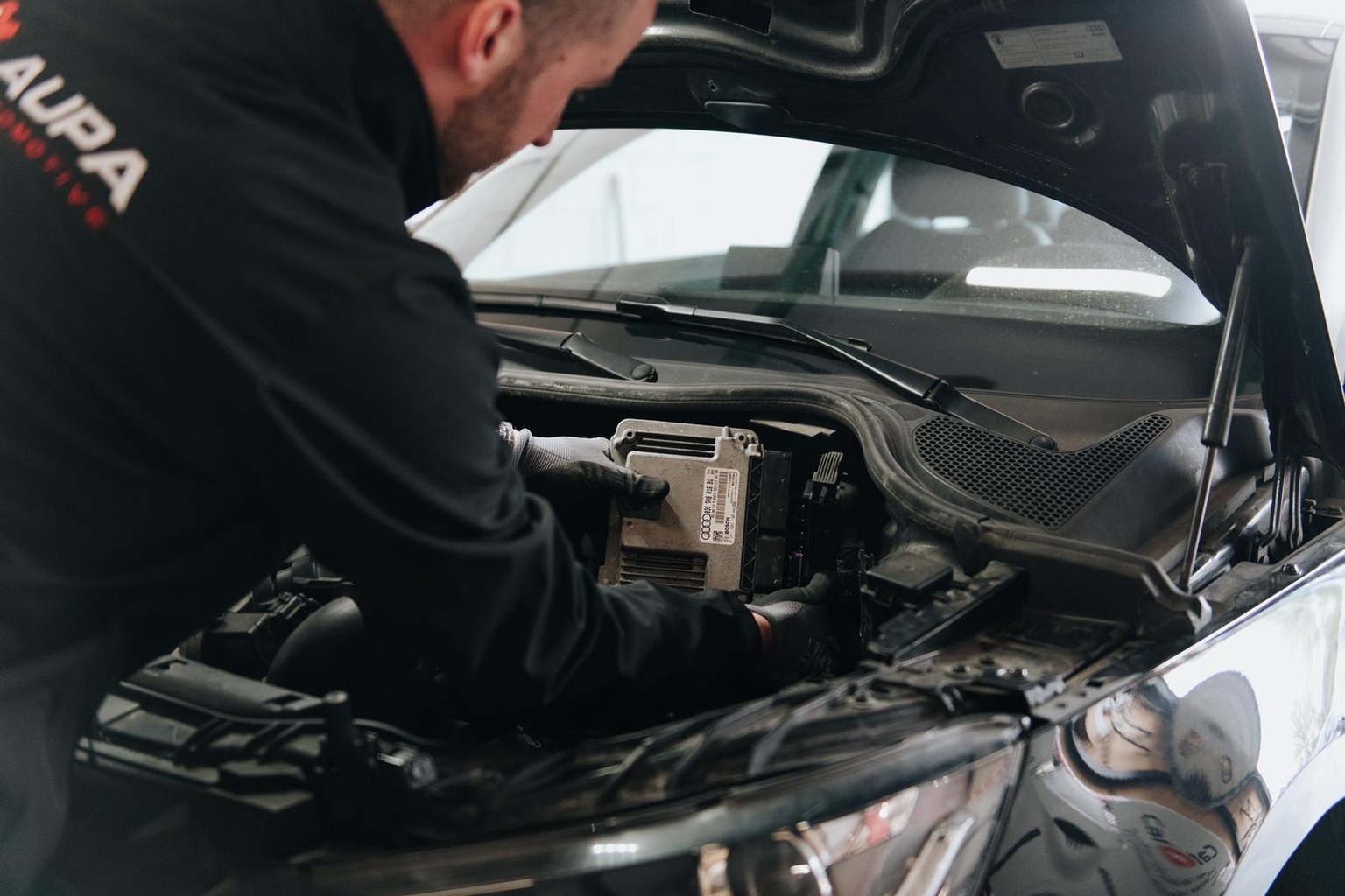 AUPA monteur aan het werk aan een hoogvolt component onder de motorkap